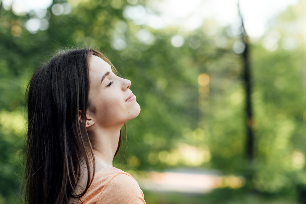 Ways To Unplug From Technology and Be Present. Unplugging from Technology and Living a More Mindful Life. Outdoor portrait of young woman enjoying nature